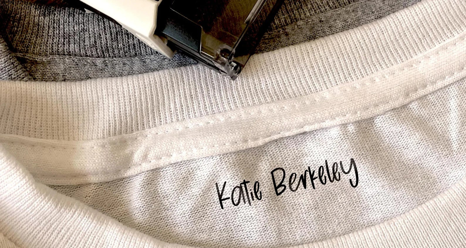 Custom fabric name stamp reading "Katie Berkeley" on the inside neckline of a white shirt