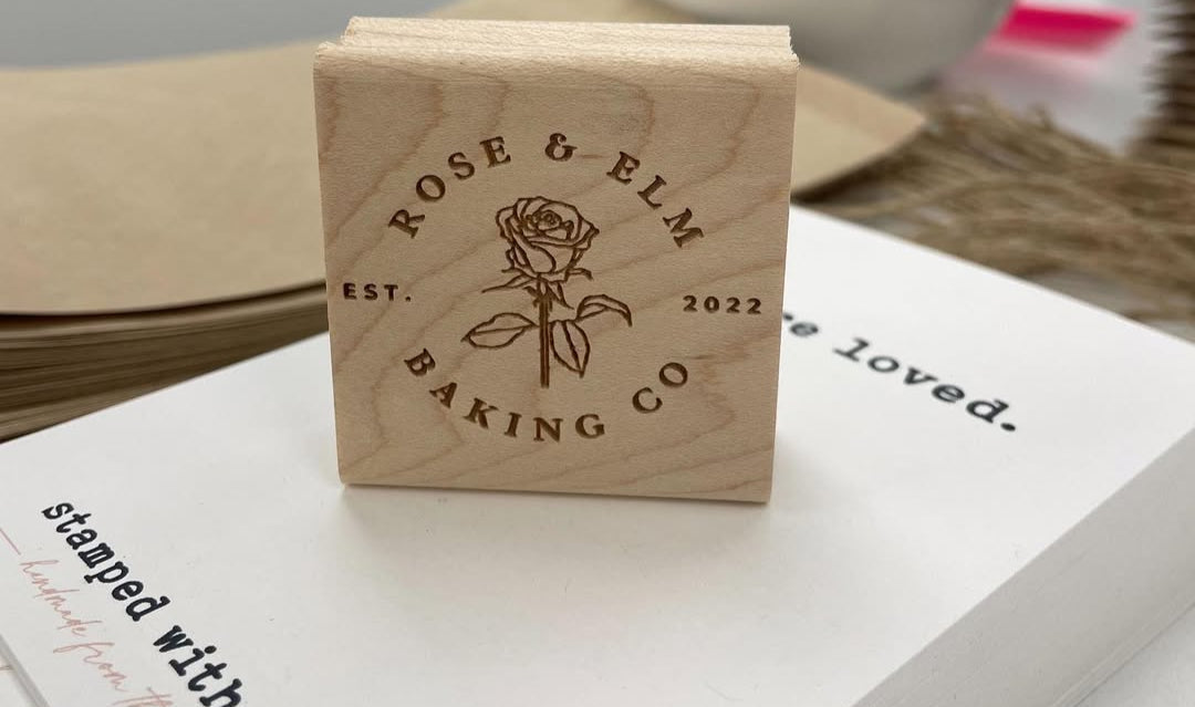 Engraved wooden logo stamp for Rose & Elm Baking Co. with floral design