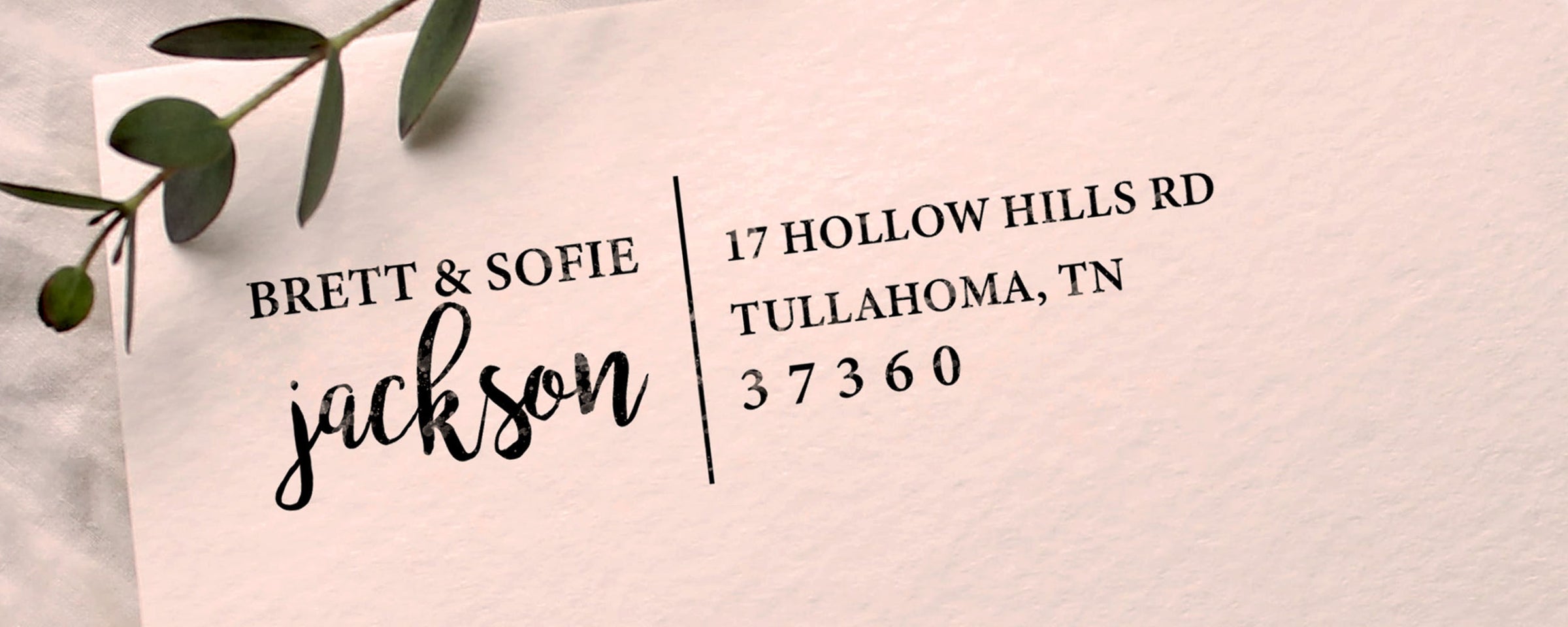 An envelope with a custom return address stamp for Brett & Sofie Jackson featuring their address in Tullahoma TN beside a sprig with green leaves