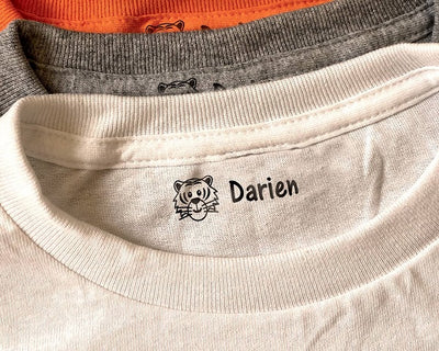 fabric stamp imprinted on the neck crease of a t shirt with a cartoon tiger face and kids name