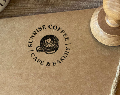 A stamped logo of Sunrise Coffee Cafe & Bakery featuring a coffee cup design on a brown paper surface.