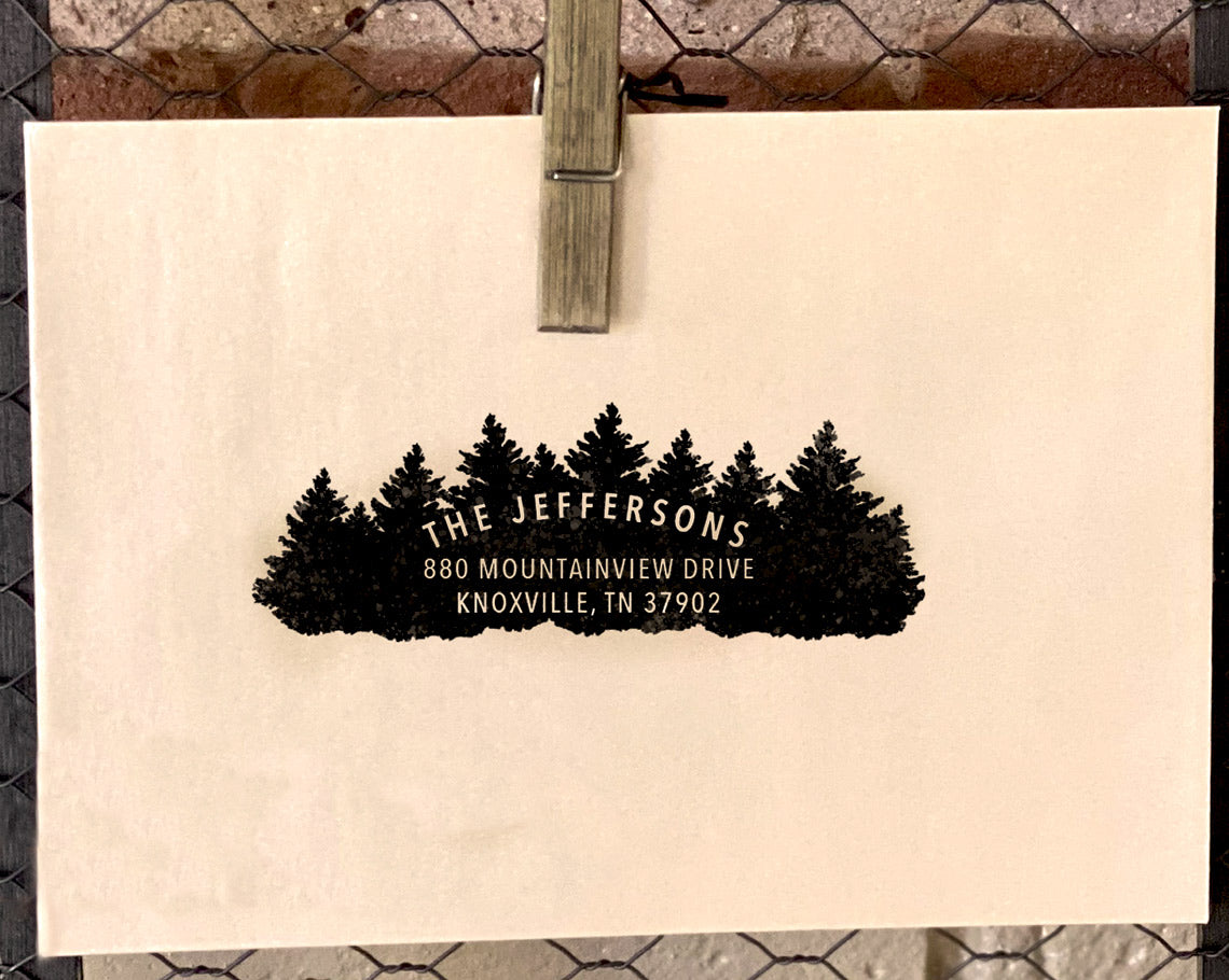 A nature themed unique return address stamp with a silhouette of pine trees above the The Jeffersons in classic typography followed by their Knoxville address