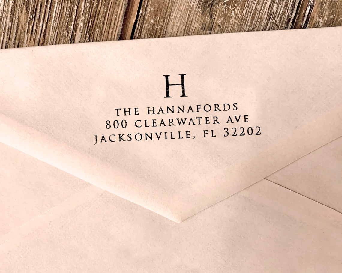 An elegant return address stamp featuring a large initial in a classic typeface
