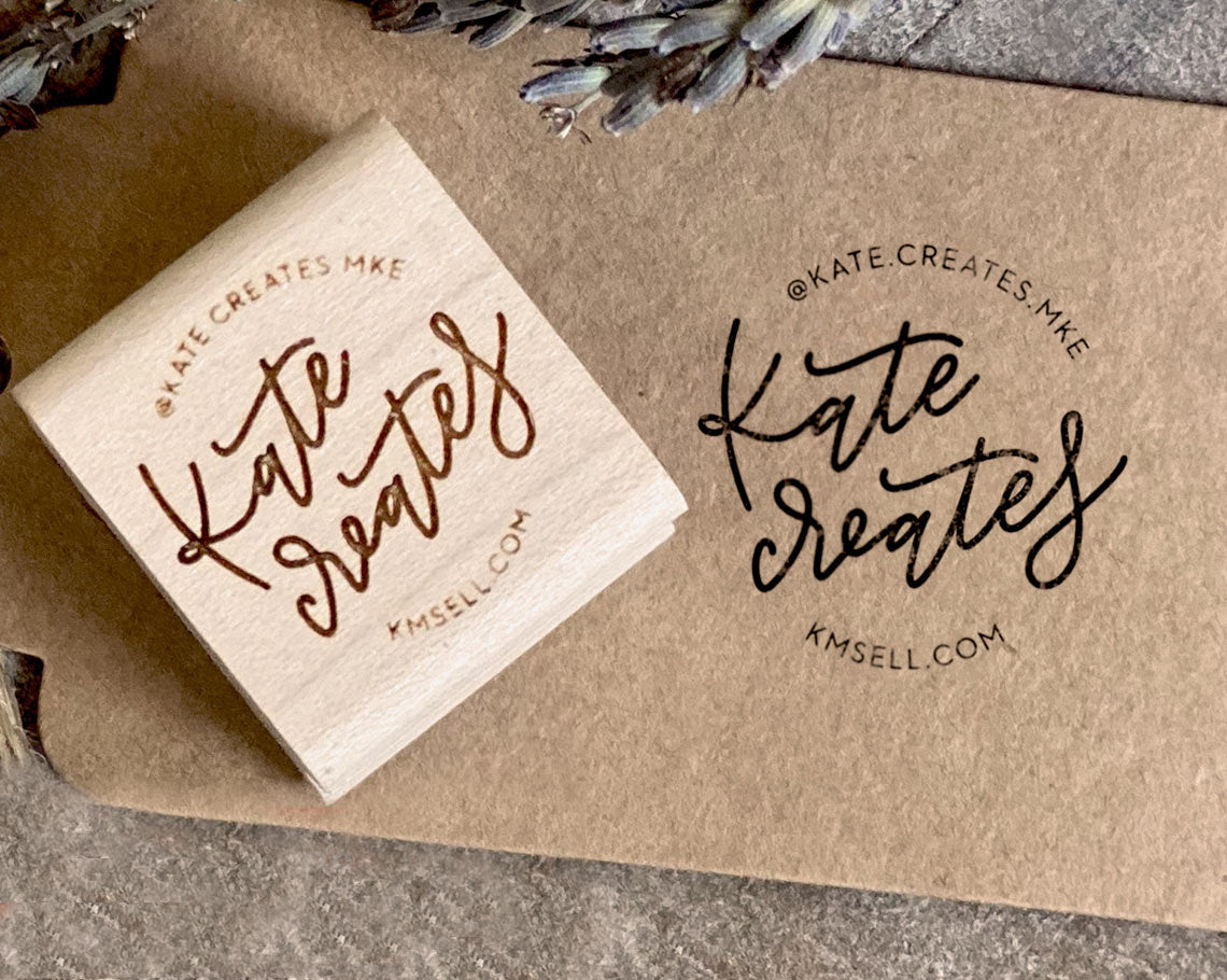 A craft paper with the black imprint of Kate Creates and the corresponding custom rubber stamp with a laser engraved logo in red ink beside it
