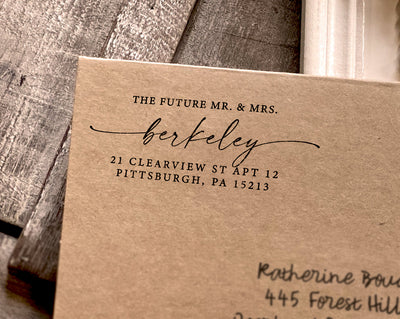 Craft paper with a black imprint of a custom wedding stamp featuring elegant script and the address for The Future Mr & Mrs Berkeley in Pittsburgh PA