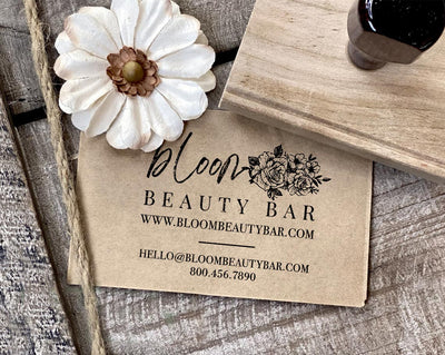 A business card for Bloom Beauty Bar featuring a floral design and contact information beside a decorative flower and a large logostamp
