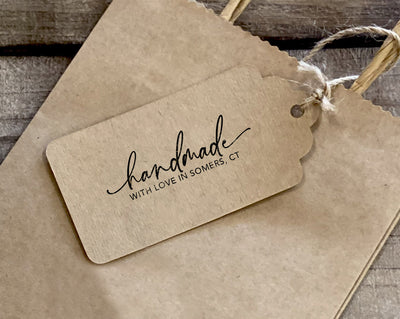 A product tag with the words handmade with love in Somers CT stamped on it attached with twine to a paper bag